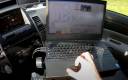 The police officer controls the robot with a laptop.